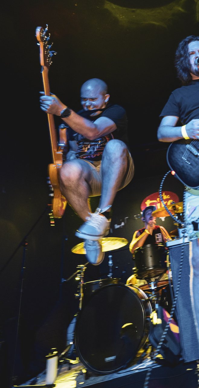 Chris jumping mid-song on stage with his band